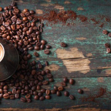 Hot coffee in a coffeepot or turk on a wooden background with coffee leaves and beans, horizontal with copy space. Top view